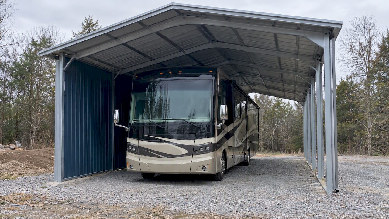 Class A RV beneath an open-sided carport with partial end wall