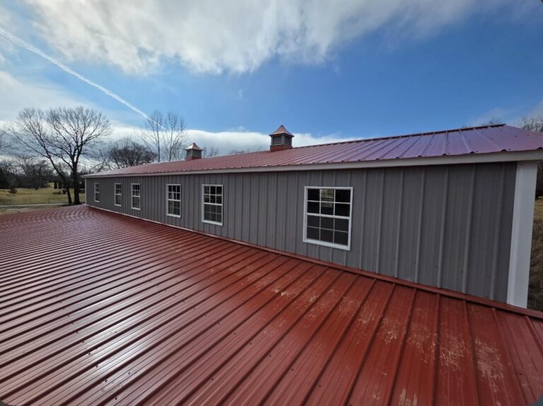 Red standing seam metal roof on a gray steel building