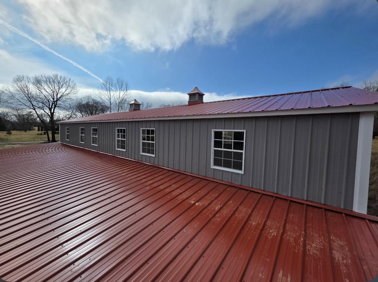 Red standing seam metal roof on a gray steel building