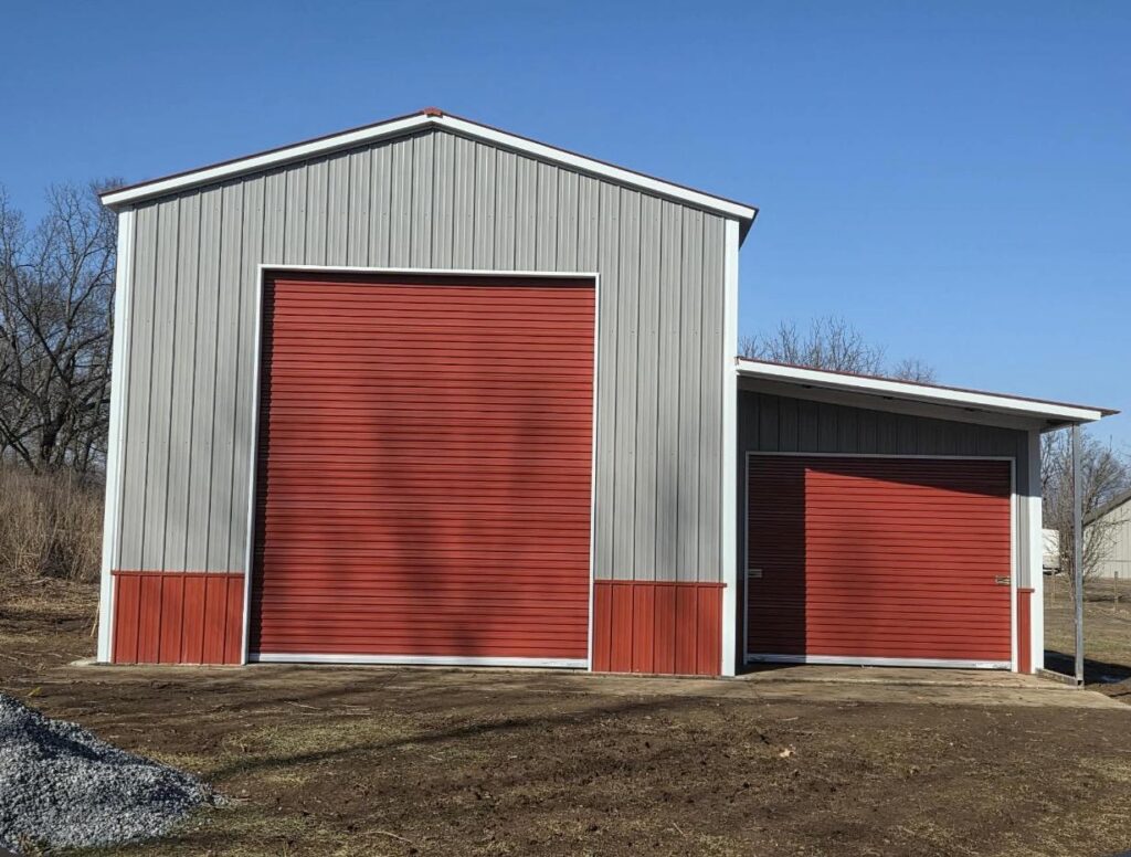Gray steel barn with red trim and two roll-up doors