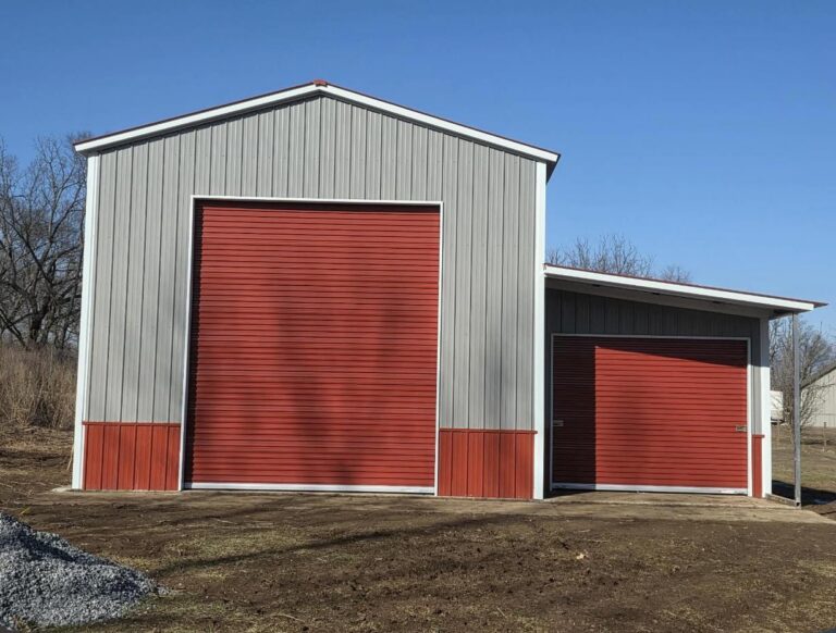 Gray steel barn with red trim and two roll-up doors