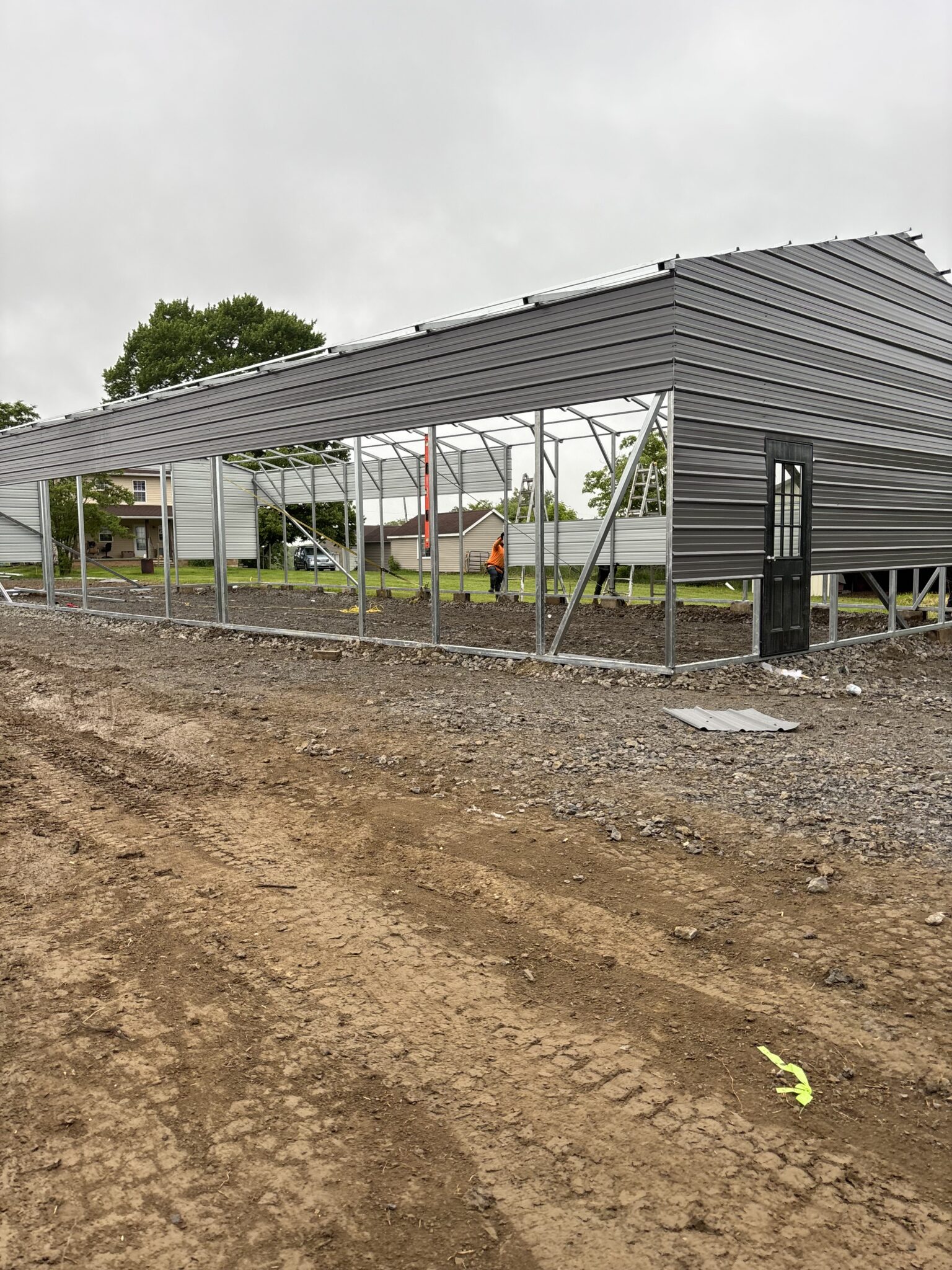 Long dark gray steel building under construction on a graded pad