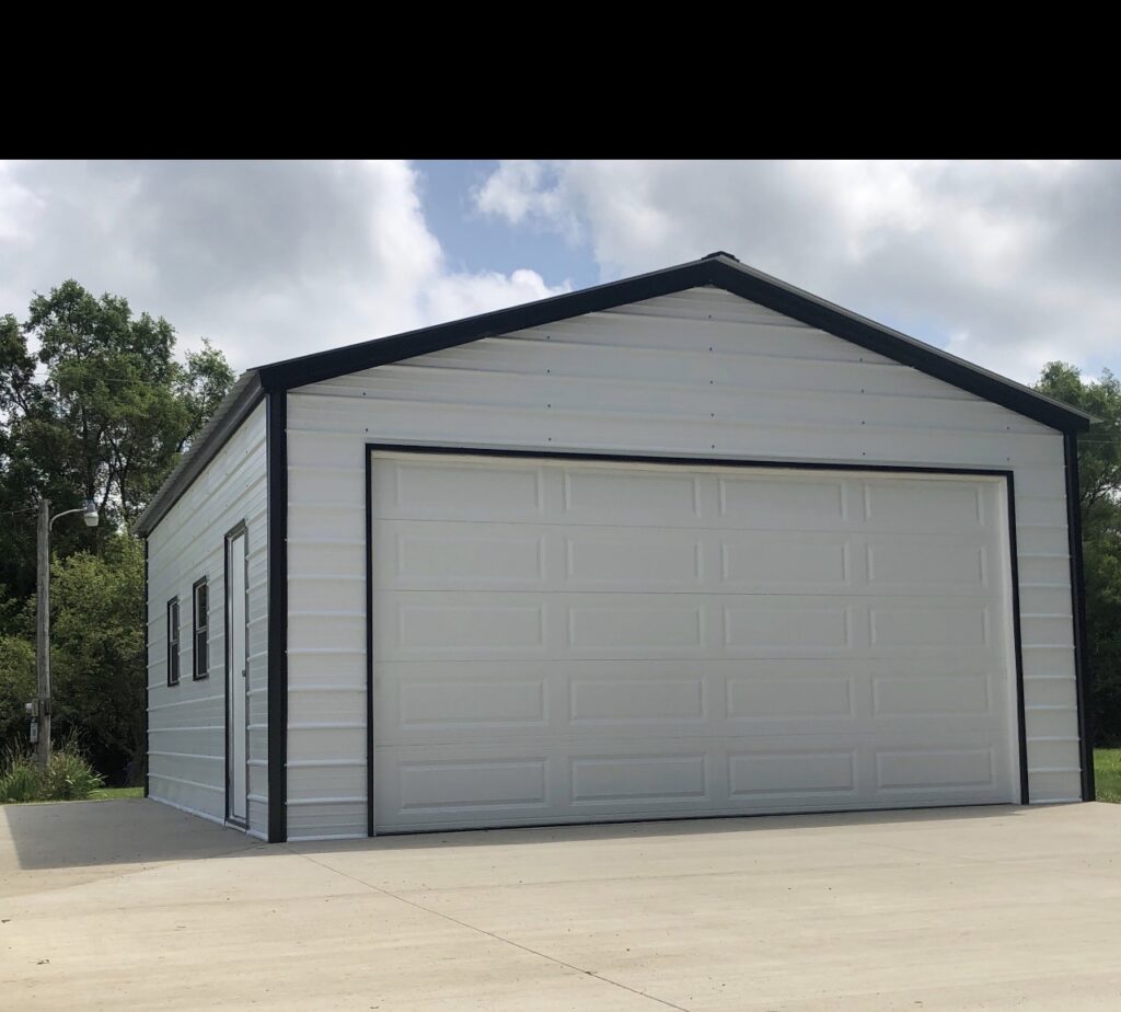 Gray steel garage with a white roll-up door and concrete apron