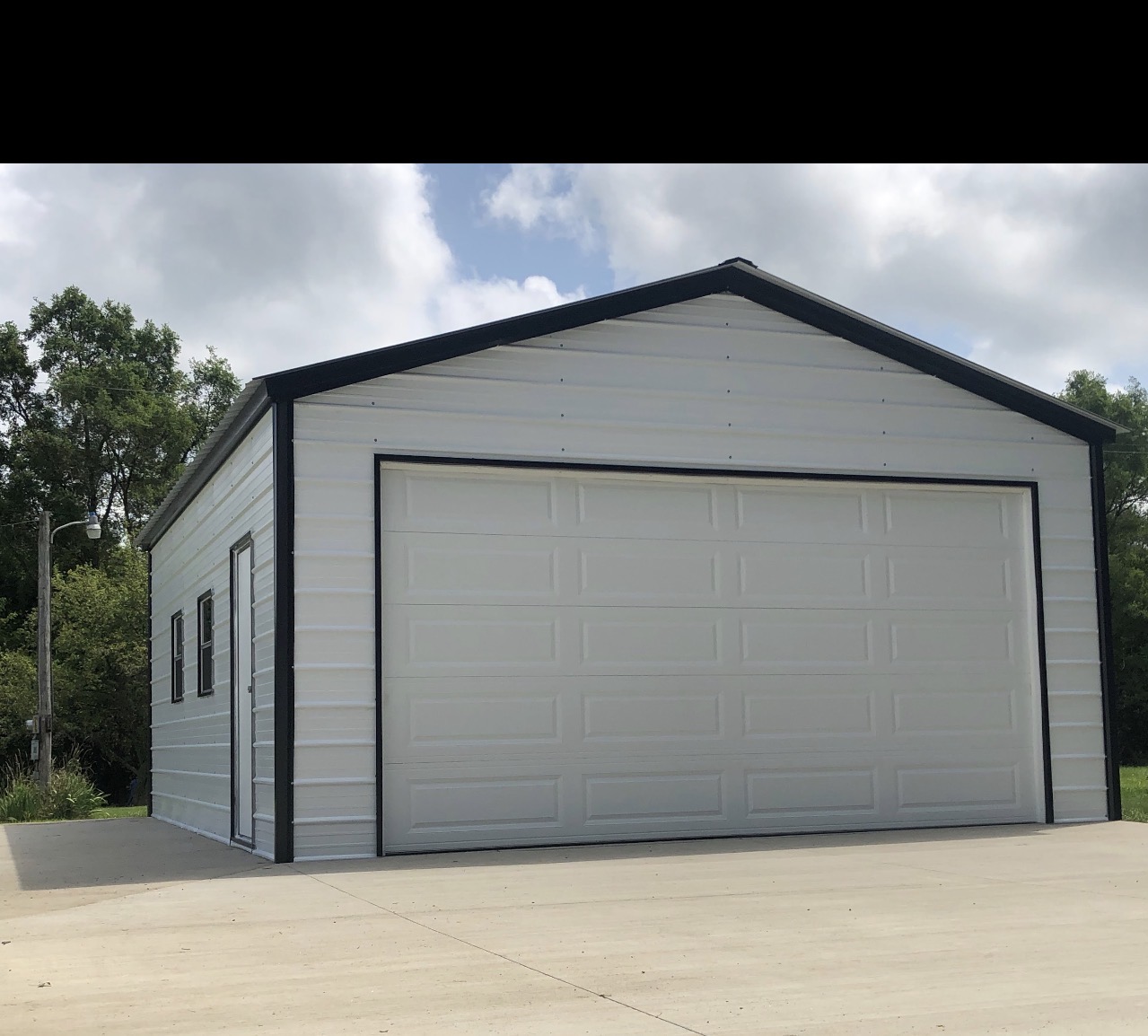 Gray steel garage with a white roll-up door and concrete apron