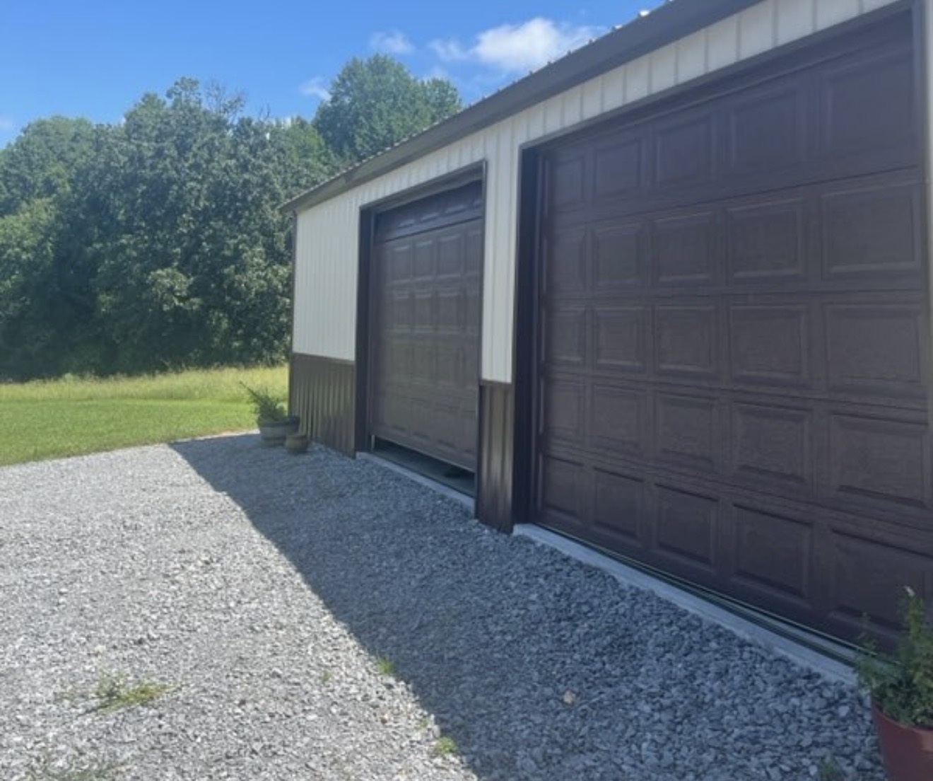 Long brown and gray steel building along a gravel drive