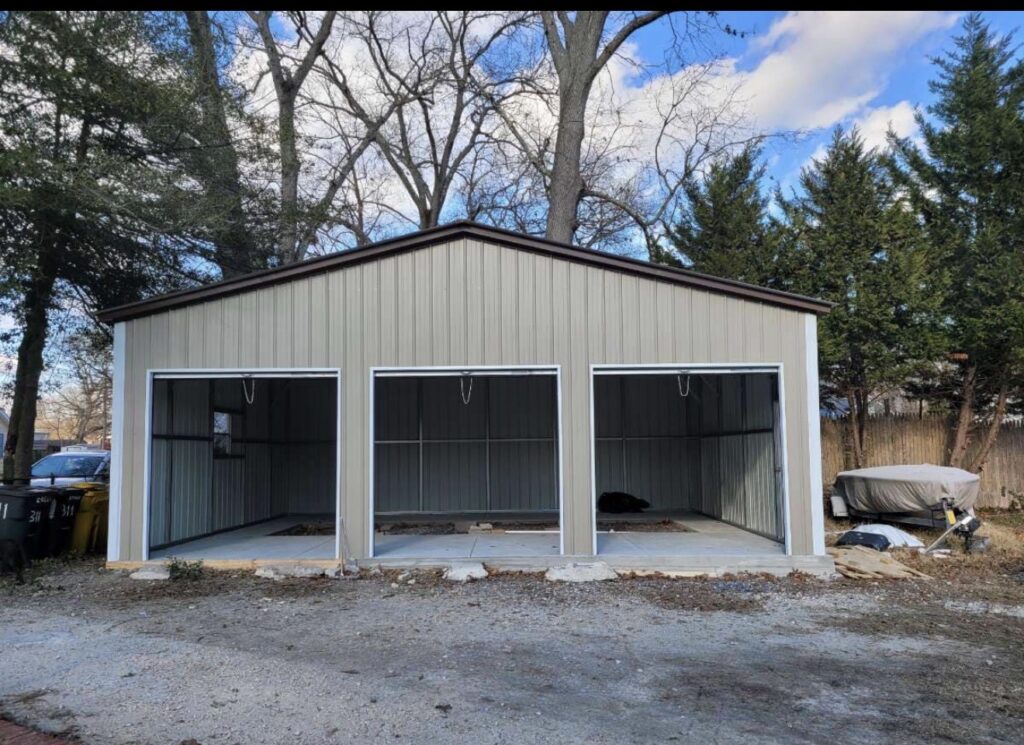 Gray and white steel garage with three open bays on a new slab