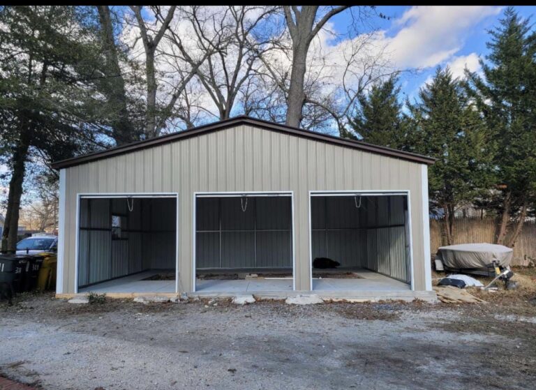 Gray and white steel garage with three open bays on a new slab