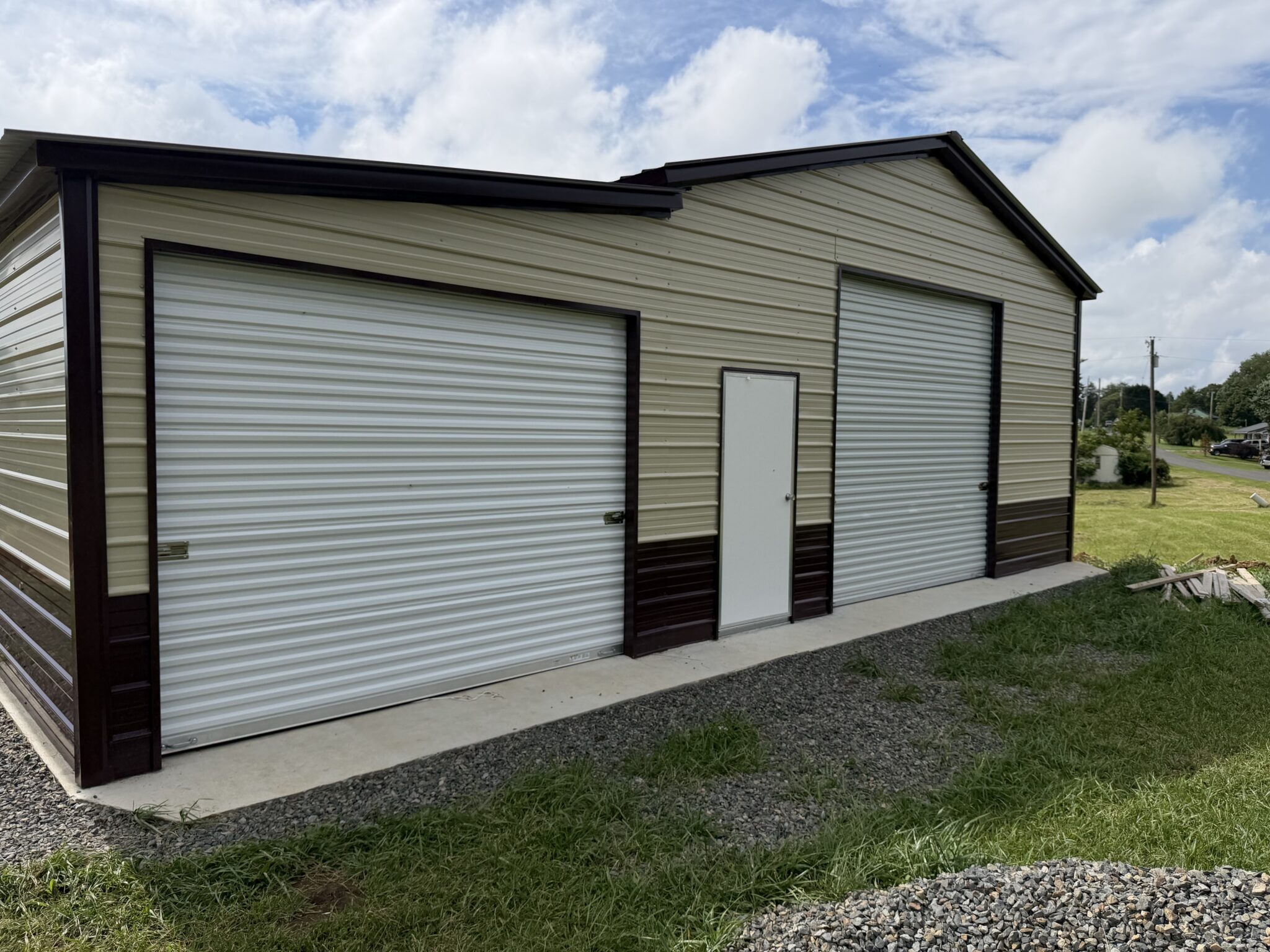 Tan steel garage with brown trim and two roll-up doors on a concrete apron