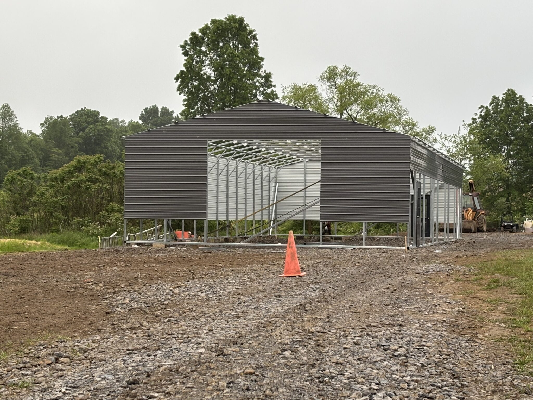 Long dark gray steel building with window openings on a gravel lot