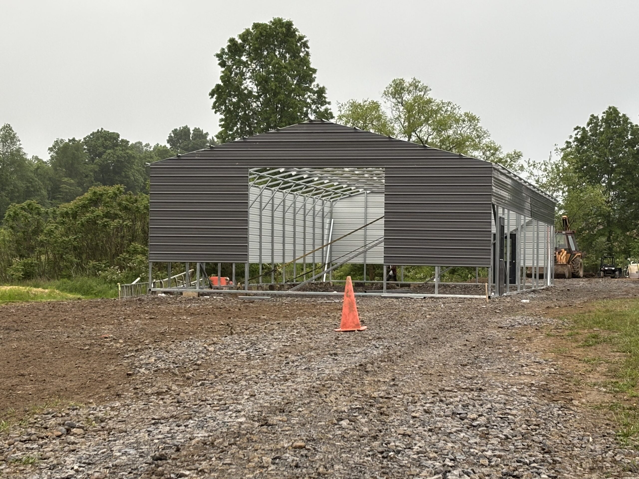Long dark gray steel building with window openings on a gravel lot