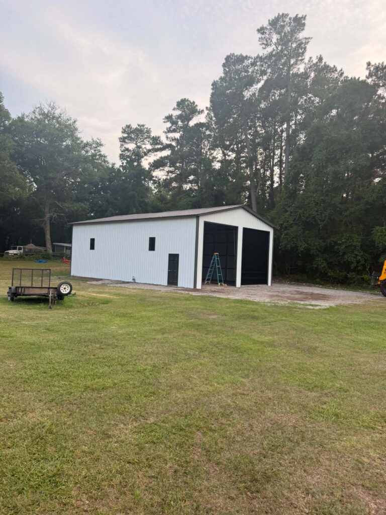 White metal building with vertical roof in a grassy yard