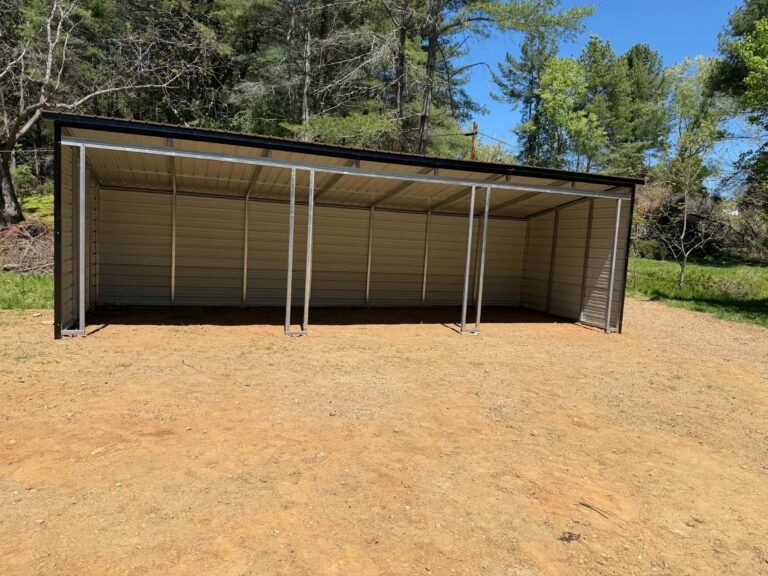 Open brown steel carport with enclosed back wall on a graded dirt pad