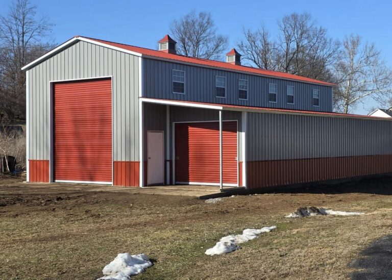 Gray and red steel barn with a tall roll-up door and lean-to