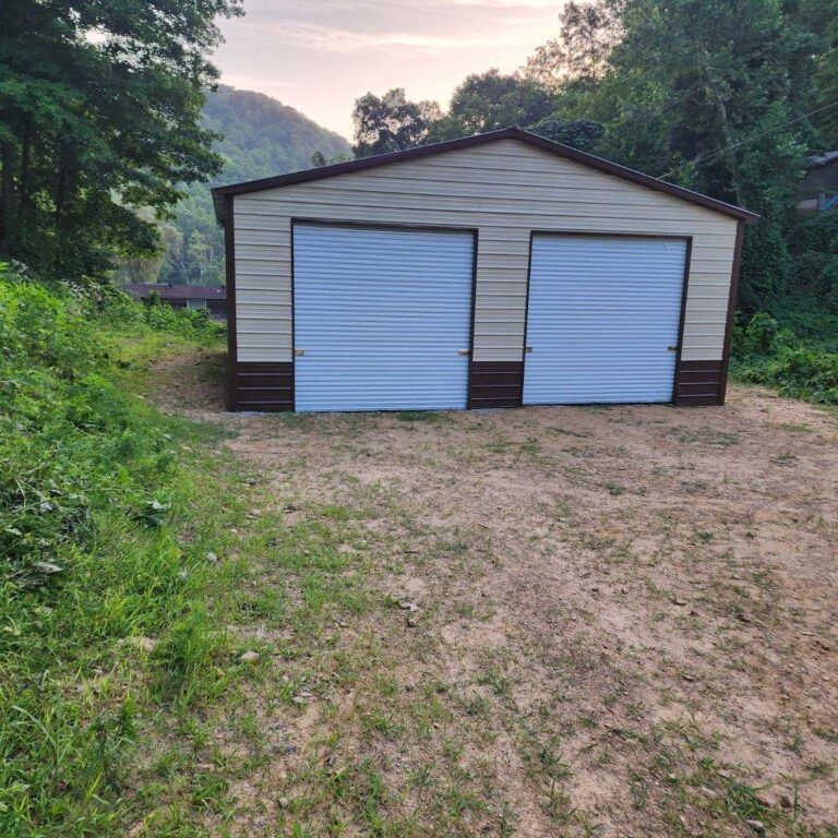 Gray steel garage with two blue roll-up doors on a gravel pad